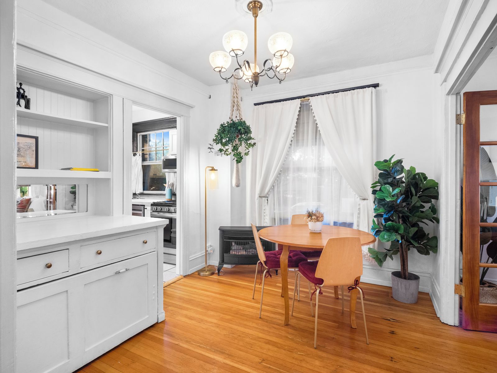 A dining area with a round table and chairs, a chandelier, and a potted plant.