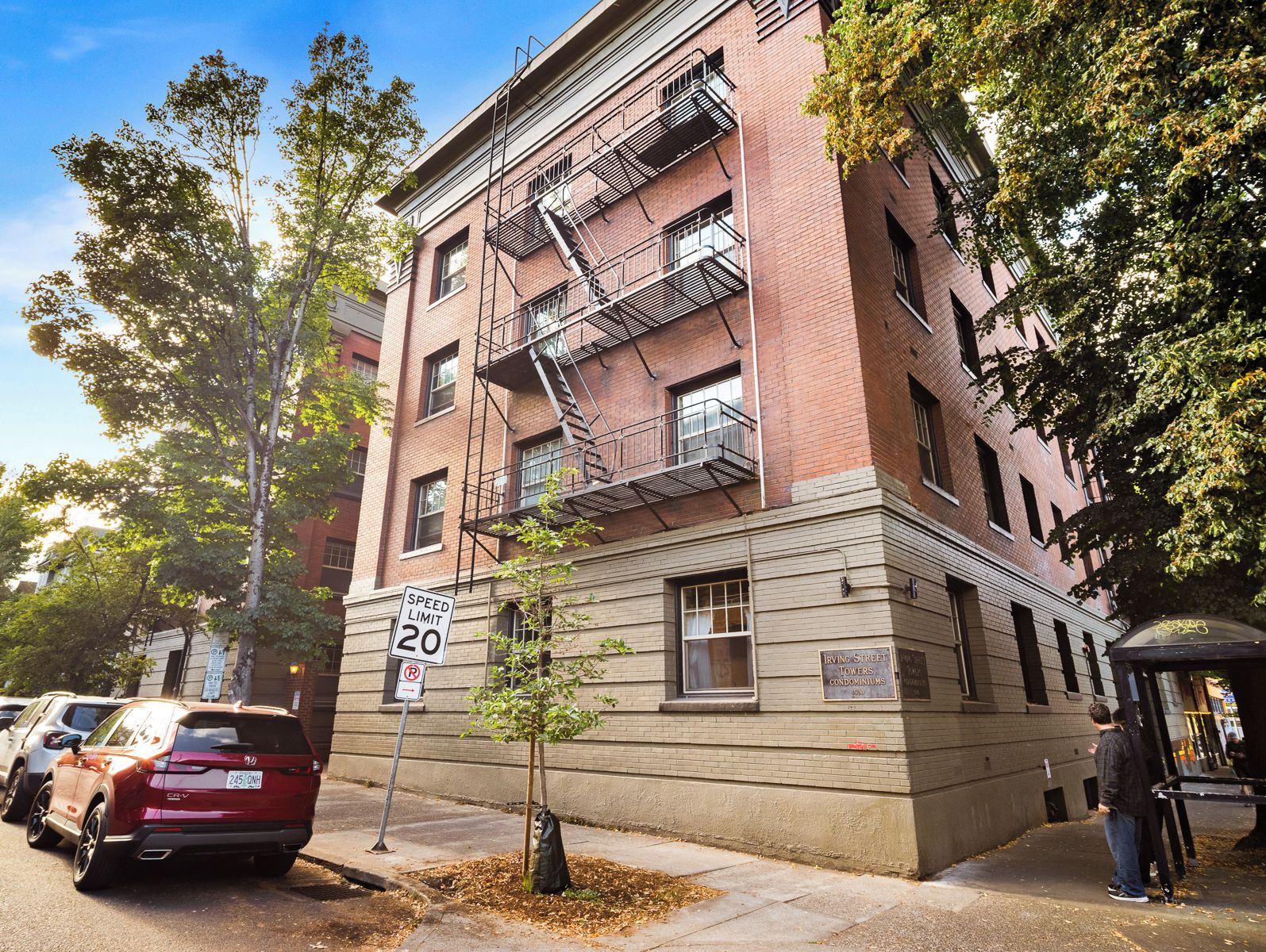 A multi-story building with a fire escape, a speed limit sign, and a sign indicating it's Irving Street Towers Condominiums.