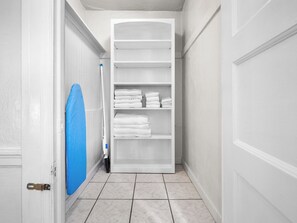 A hallway with a white door, a blue towel hanging on the wall, and a white closet with shelves.
