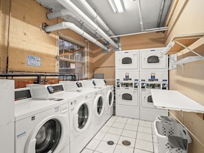 Een wasserette met meerdere wasmachines en drogers, een bedieningspaneel en een bord met instructie om de timer in te stellen.
