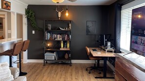 Un salon moderne avec un ventilateur de plafond, une bibliothèque, un bureau et un canapé.