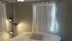 Une chambre à coucher avec un lit, un ventilateur de plafond et deux lampes de chevet.