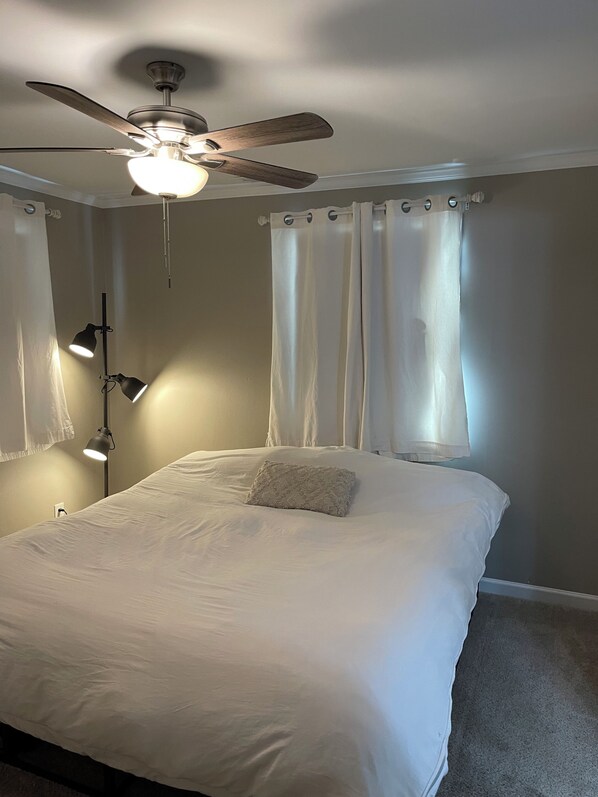 Quarto com cama, ventilador de teto e duas luminárias de cabeceira.