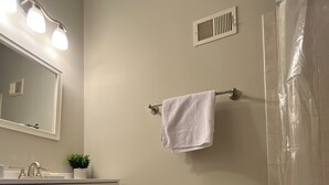 A bathroom with a toilet, sink, mirror, towel rack, and shower curtain. - Stylish Townhouse by Carrol Park, M&T Bank Stadium (Baltimore)