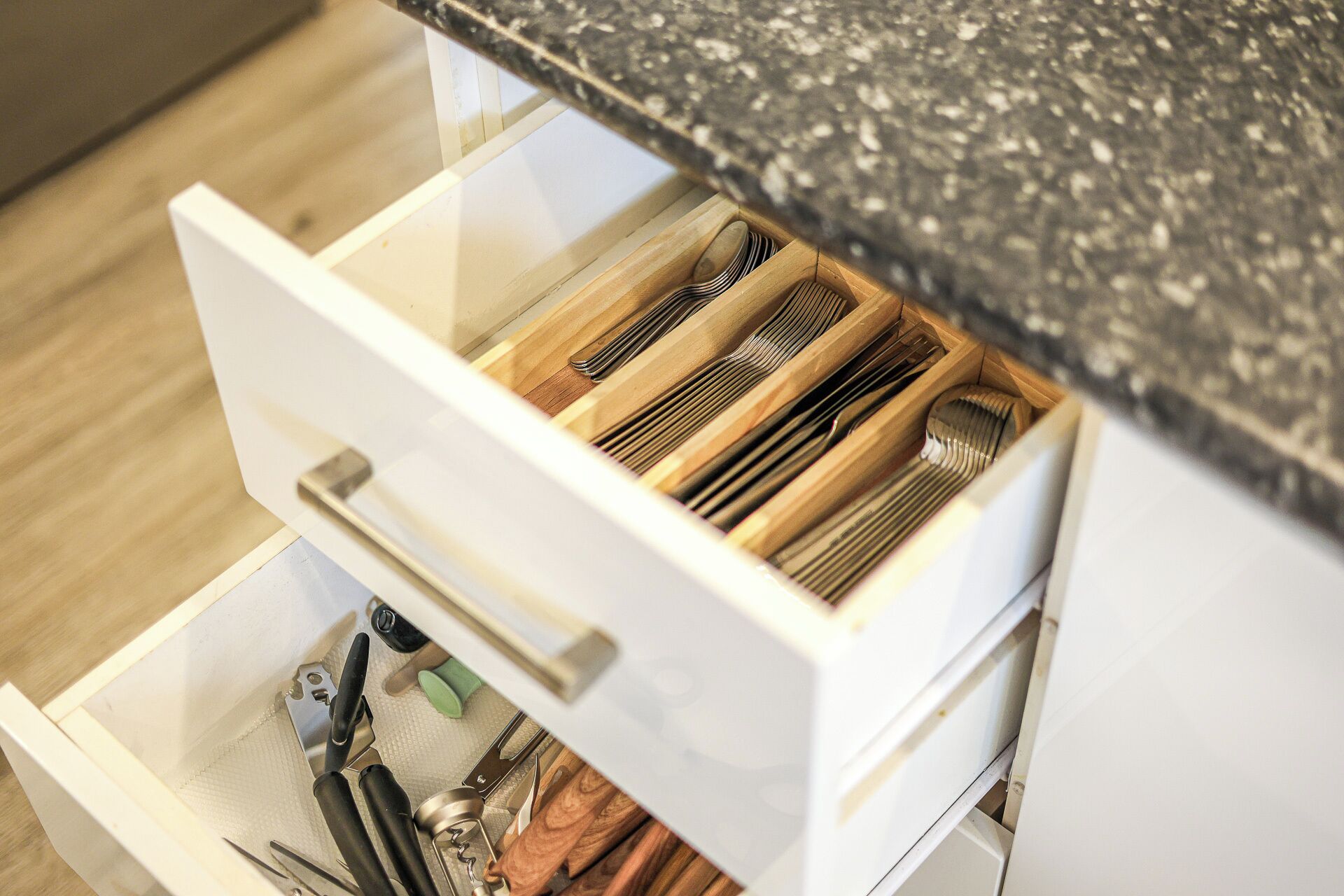 A kitchen drawer with utensils and a cutting board.