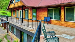 A wooden cabin with a red roof, large windows, and a balcony with chairs. - Yellow River Lodge 6-bedroom cabin w/Pool &Hot Tub & Pool Table (Waterville)