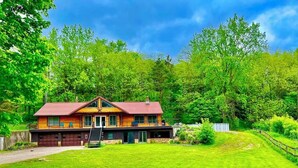 A two-story house with a red roof, a front porch, and a well-maintained lawn. - Yellow River Lodge 6-bedroom cabin w/Pool &Hot Tub & Pool Table (Waterville)