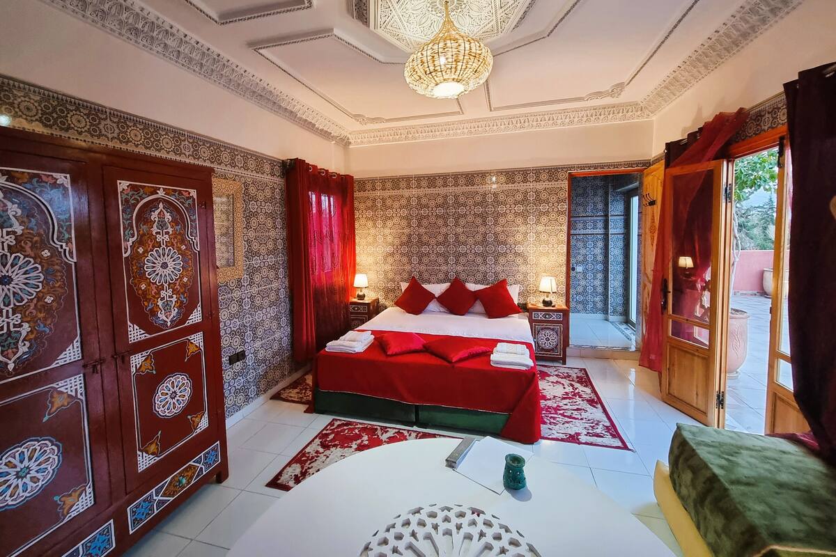 Una habitación tradicional con cama, una mesa y una araña.