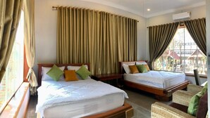 Une chambre d’hôtel avec deux lits, un ventilateur de plafond et une vue sur l’extérieur.