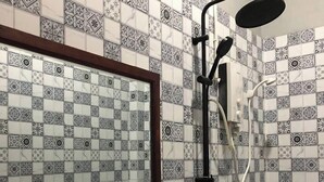 Une salle de bain dotée d’un grand miroir, d’un lavabo avec un receveur et d’une douche avec un pommeau de douche amovible.