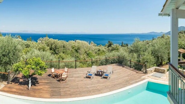 Un espace aménagé au bord de la piscine, avec vue sur la mer, une terrasse en bois et des chaises longues.