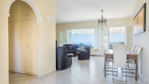 Un vaste espace de vie comprenant une table et des chaises de salle à manger, un canapé et une vue sur l’océan.