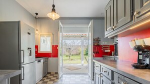 Une cuisine moderne avec des armoires grises, un carrelage à motifs et un pare-feu rouge.