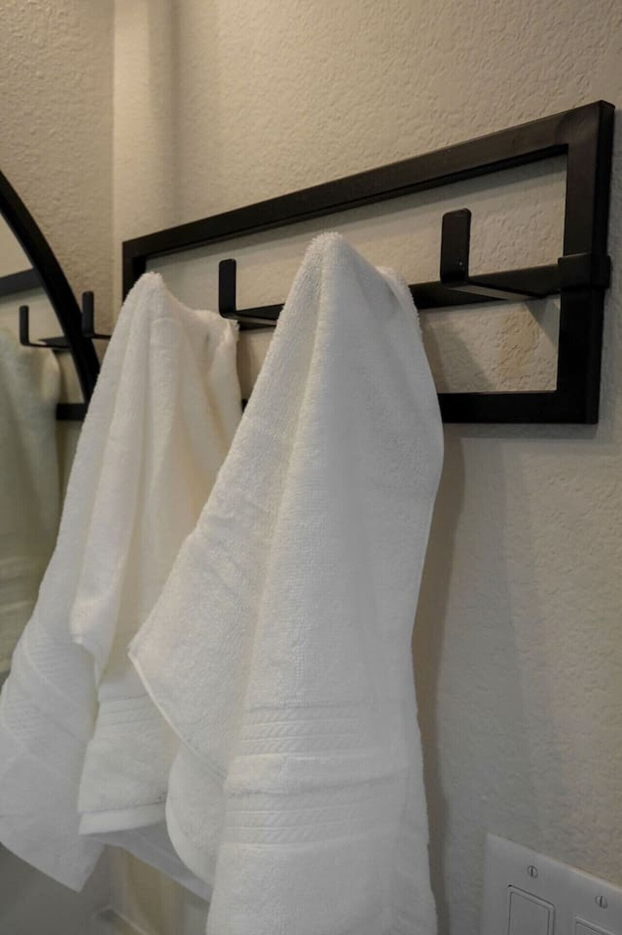 Een badkamer met een handdoekrek met twee witte handdoeken.