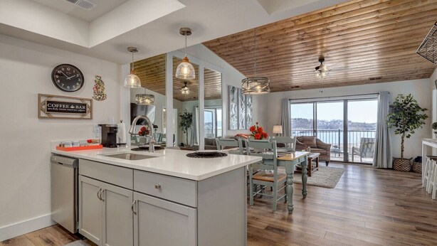 A modern kitchen with a central island, a coffee bar sign, and a dining area with a view. - Lakeview Getaway at Kimberling Crossing (Kimberling City)