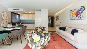 Una sala de estar moderna con un sofá, un comedor con sillas y una mesa, y una cocina al fondo.