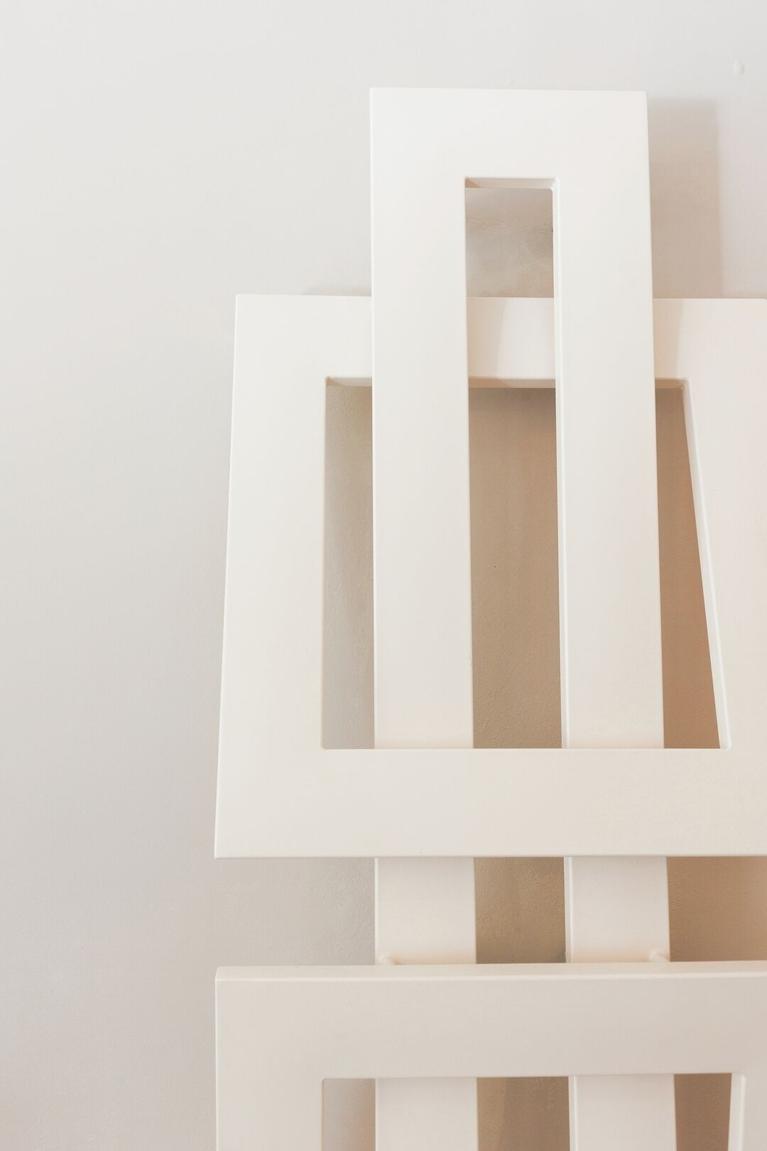 A white, minimalist wall with geometric cutouts.