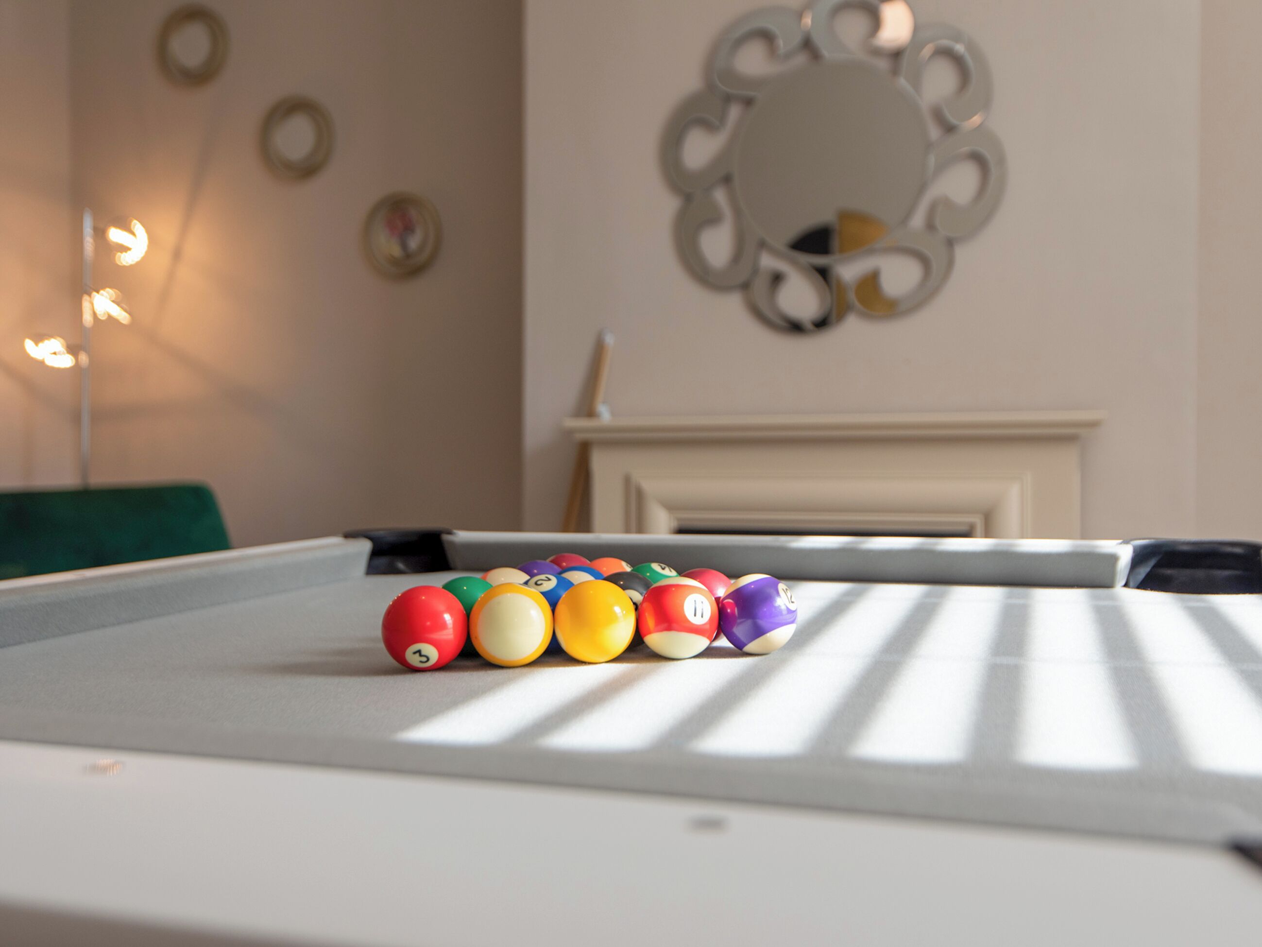 A pool table with billiard balls in a room with a fireplace and wall decor.