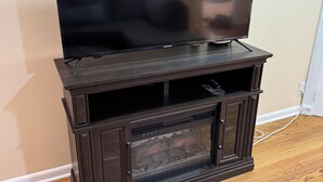 Eine dunkle Holz-Unterhaltungsecke mit einem Flachbildfernseher obenauf und einem eingebauten Kamin darunter.