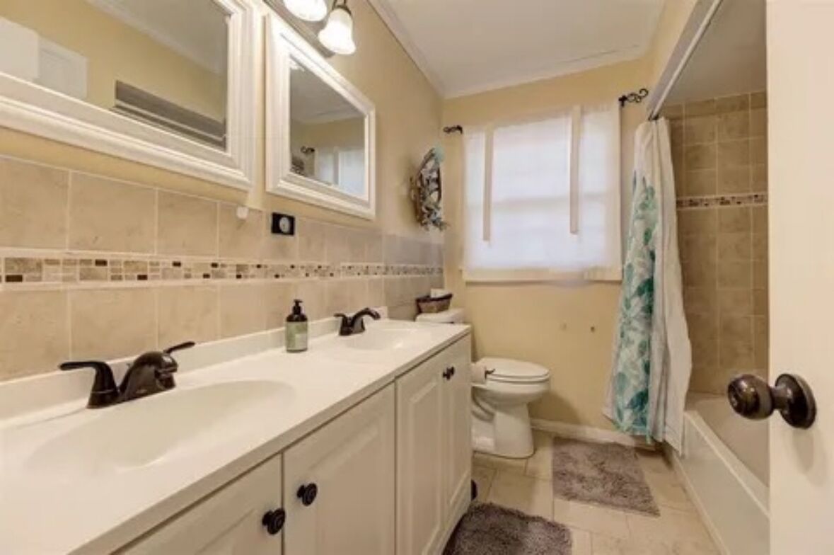 Een badkamer met een wit wastafel, spiegel en toilet.