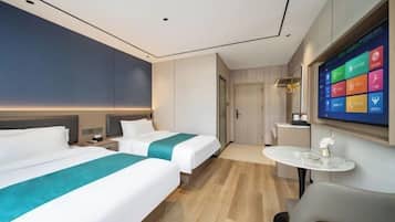 Habitación de hotel con dos camas, un televisor, una mesita y una puerta.