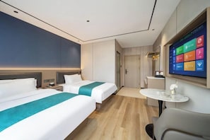 A hotel room with two beds, a TV, a small table, and a door.