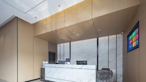 A modern reception area with a marble counter, wooden paneling, and a digital display on the wall. - Shanghai Eagle Hotel (Shanghai)