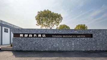 Un muro de piedra con un letrero del Yingdu Business Hotel.