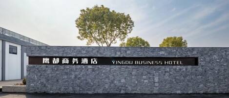 A stone wall with a sign for the Yingdu Business Hotel.