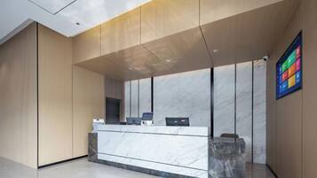 A reception desk with a marble top, a digital display, and a wall-mounted screen.