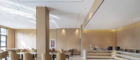 A modern hotel lobby with a central column, seating area, and a counter.