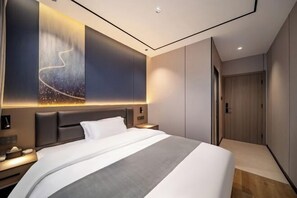A modern hotel room with a large bed, a nightstand, a wall-mounted light, and a door. - Shanghai Eagle Hotel (Shanghai)