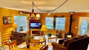 Un acogedor interior de cabaña de madera con una mesa de comedor, un sofá y una chimenea.