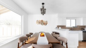 Un comedor moderno con una larga mesa de madera, sillas tapizadas en tonos beige y un centro de mesa con frutas.