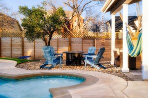 A backyard with a swimming pool, two Adirondack chairs, a fire pit, and a hammock. - Pool+HotTub+Firepit+Grill+Billiards+MiniGolf+PS4 (Pflugerville)