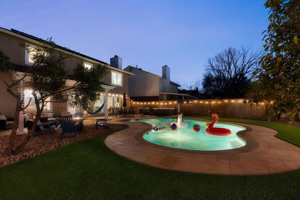 A backyard with a swimming pool, inflatable flamingos, and a hammock. - Pool+HotTub+Firepit+Grill+Billiards+MiniGolf+PS4 (Pflugerville)