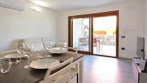 A modern dining area with a table set for four, a sofa, and a view of the outdoor patio. - Amazing apartment in Olia Speciosa with WiFi (Olia Speciosa)