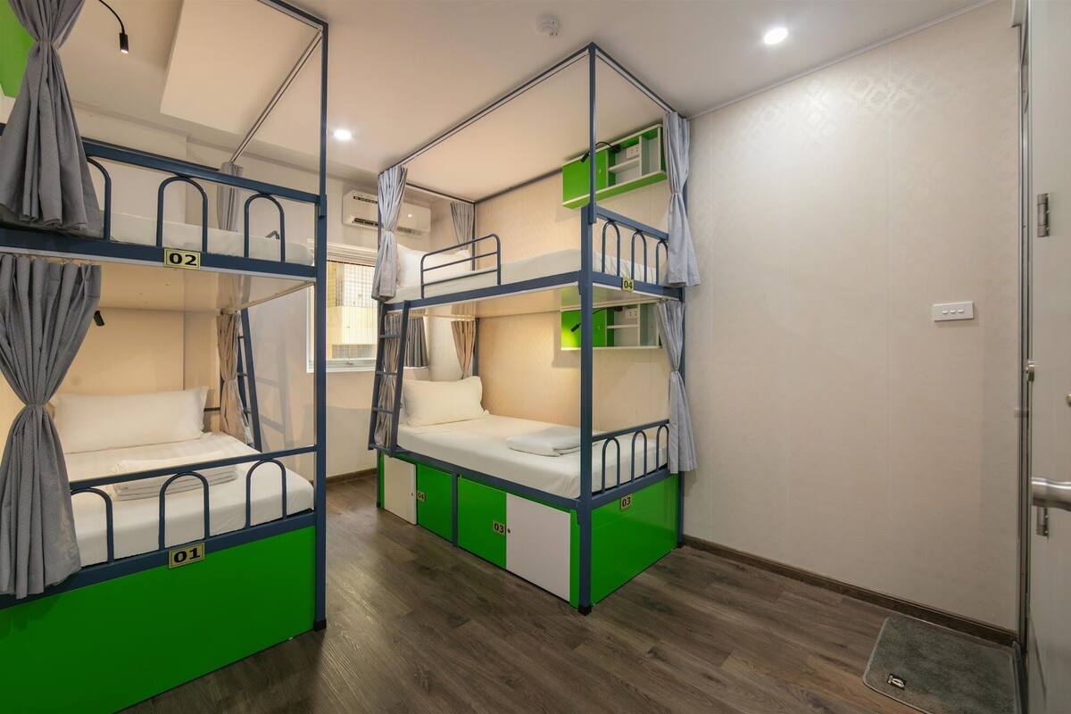 A dormitory room with bunk beds, numbered from 01 to 04, and a small green shelf unit.