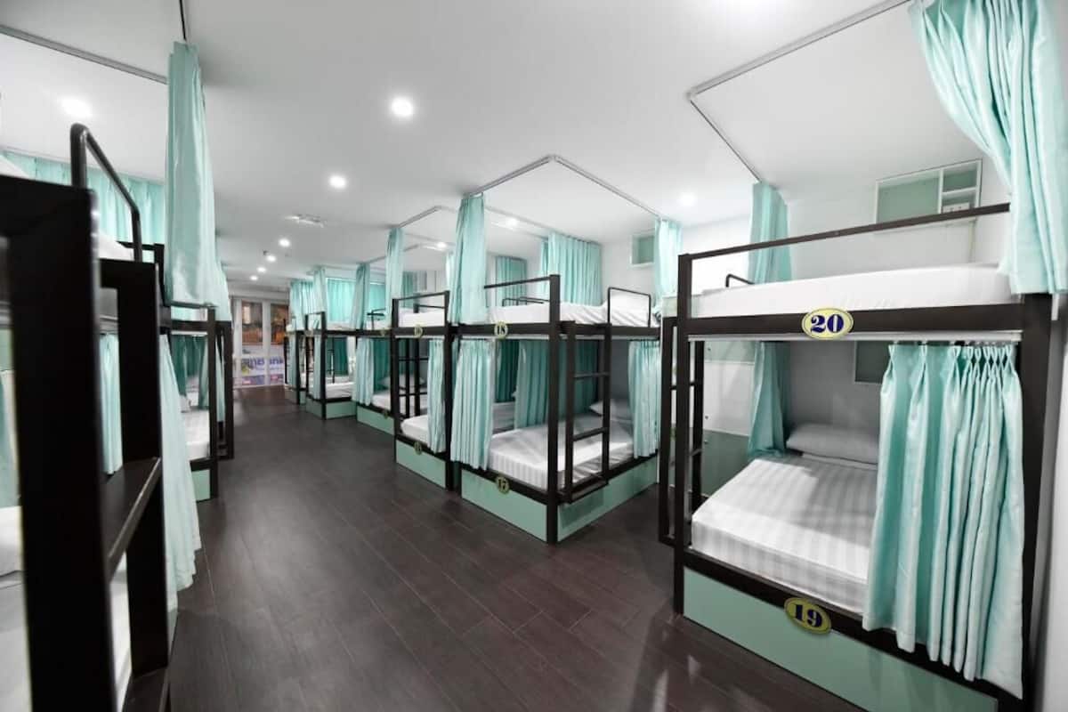 A hotel room with bunk beds, teal curtains, and a wooden floor.