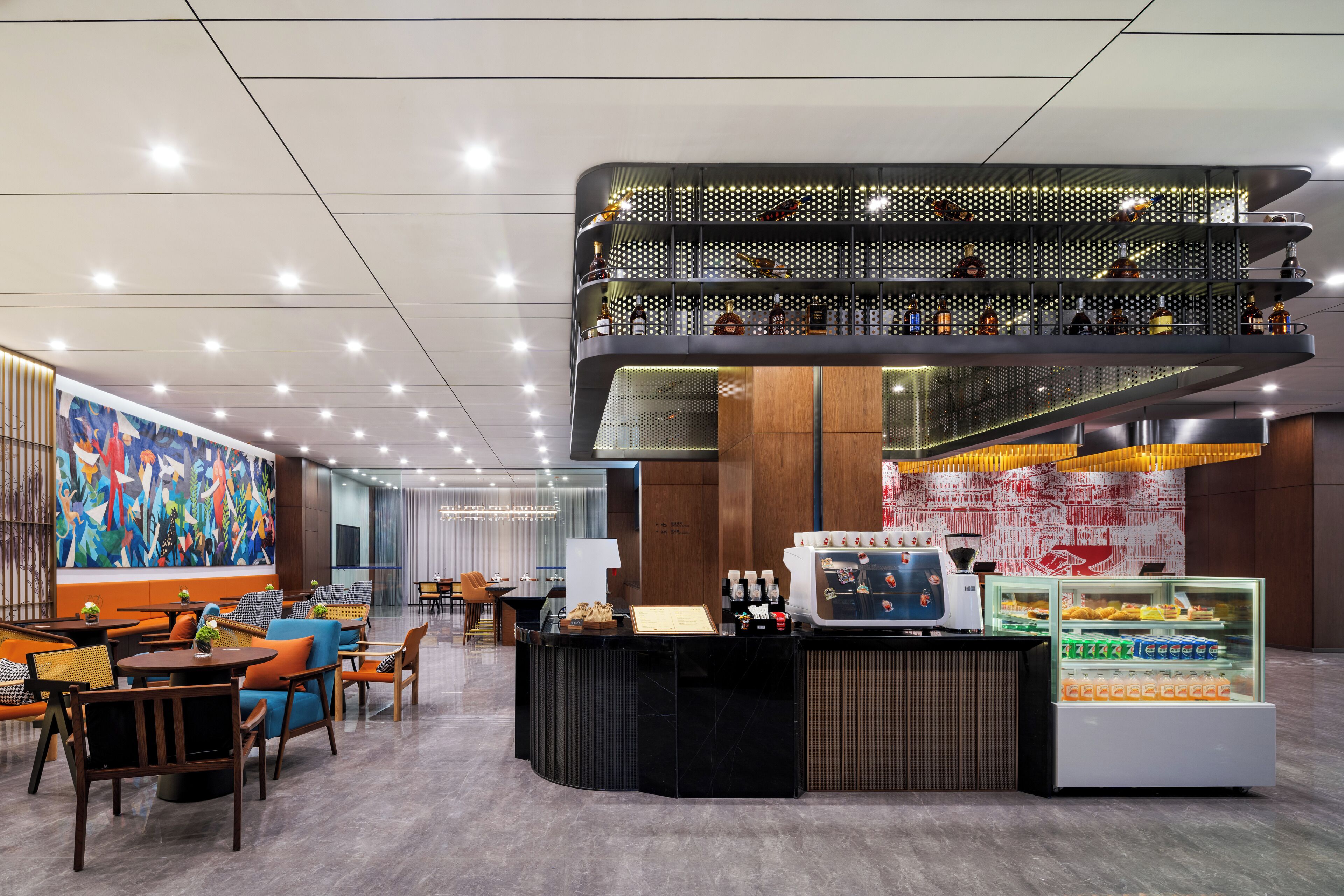 Un hall d’hôtel moderne avec un comptoir d’accueil central, un espace salon et un mur décoratif.
