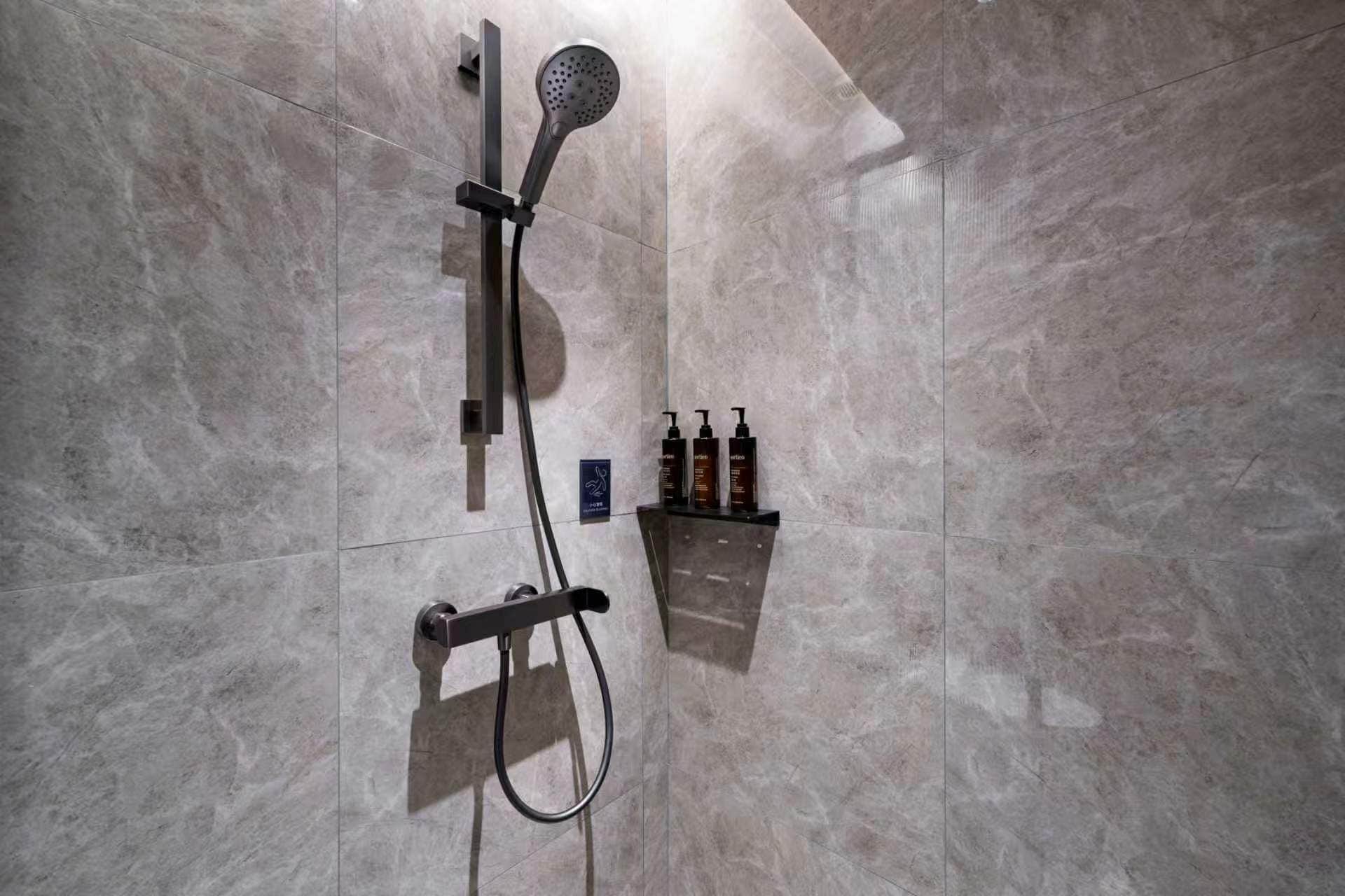 A modern shower with a handheld showerhead and a wall-mounted control panel.