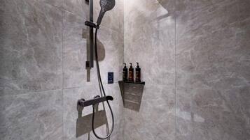 A modern shower with a handheld showerhead and a wall-mounted control panel.