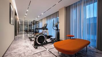 Ein modernes Fitnessstudio mit Trainingsgeräten, einer Bank und großen Fenstern.