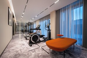Un gimnasio moderno con equipo de ejercicio, una banca y ventanas amplias.