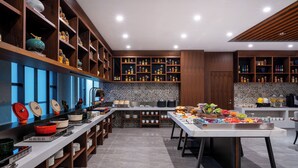 A modern kitchen with wooden shelves, a long counter, and a variety of kitchenware. - UrCove By Hyatt Yangzhou Dongguan Street (Yangzhou)