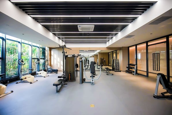 Ein modernes Fitnessstudio mit Trainingsgeräten, großen Fenstern und einem klaren Design.