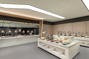 A modern buffet setup with a variety of food items and a chef preparing food. - Keymore Residence Guangzhou (Guangzhou)