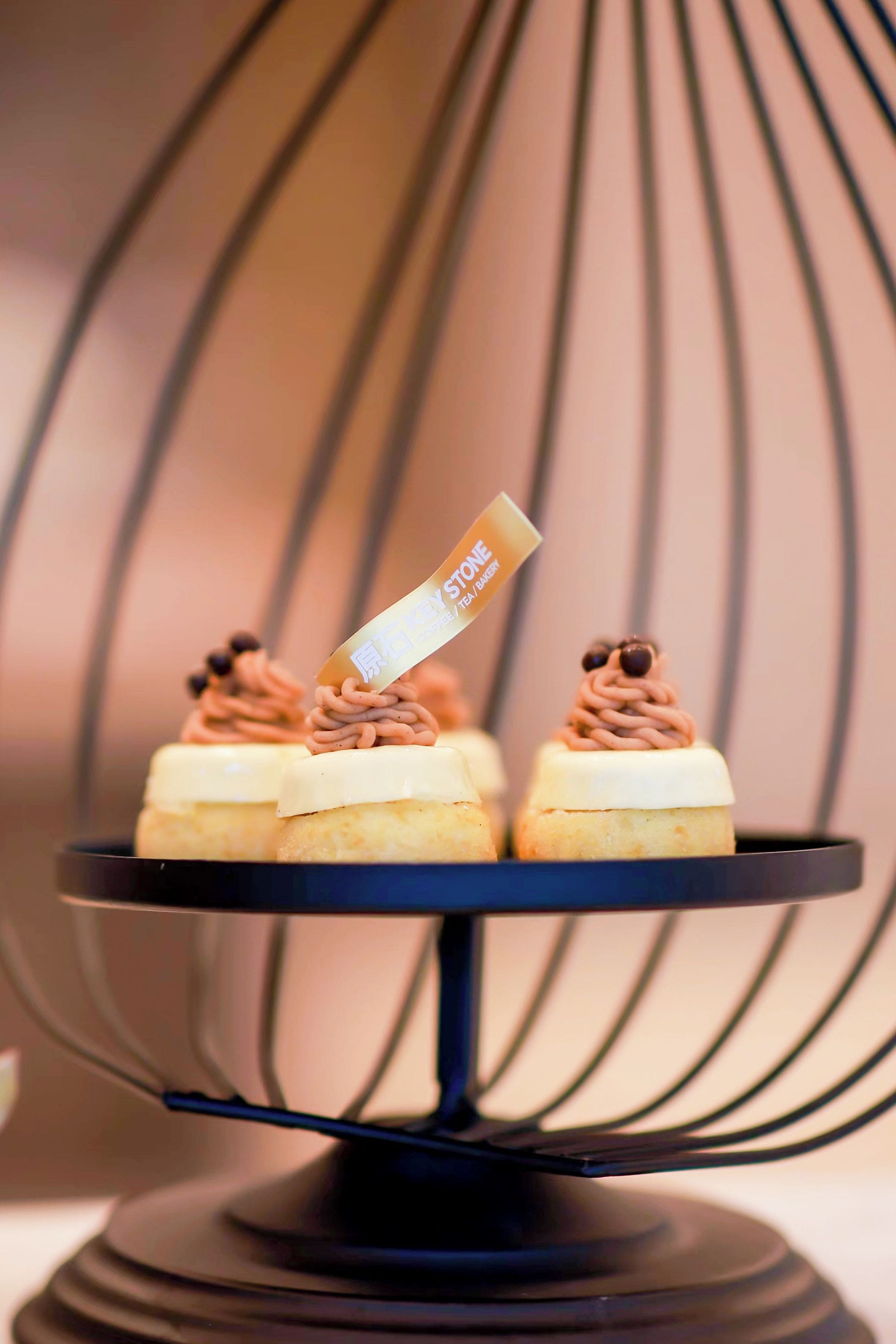 A dessert stand with a cake and a sign that reads 'KEY STONE TEA/BAKERY'.