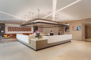 A modern hotel reception area with a curved reception desk, a large chandelier, and a wall-mounted digital display. - Keymore Residence Guangzhou (Guangzhou)