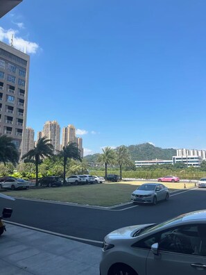 A parking lot with several cars, a grassy area, and buildings in the background. - Keymore Residence Guangzhou (Guangzhou)